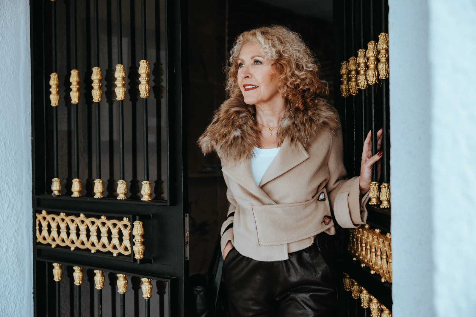 Personal Brand Portrait einer Unternehmerin mit lockigem Haar an einer schwarzen Tür mit goldenen Verzierungen