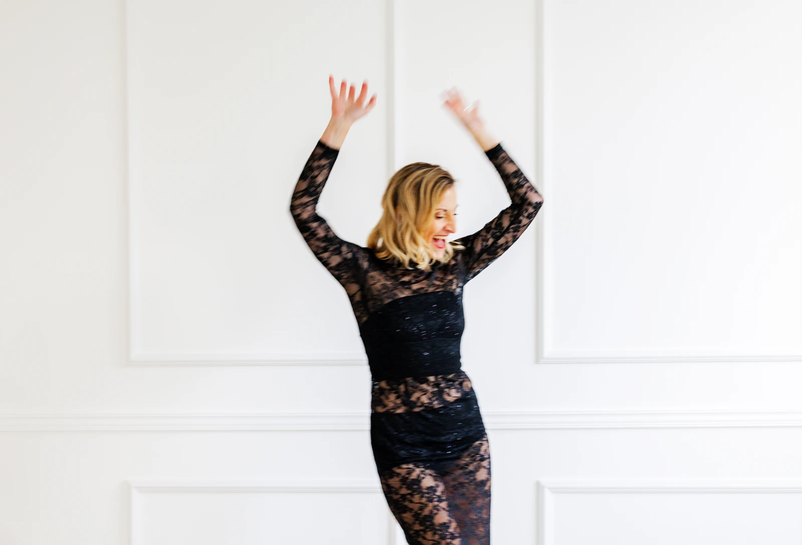 Jacqueline Schürer tanzt im Spitzenkleid Jacqueline Schürer tanzt im schwarzen Spitzenkleid mit angehobenen Armen vor einer hellen Wand