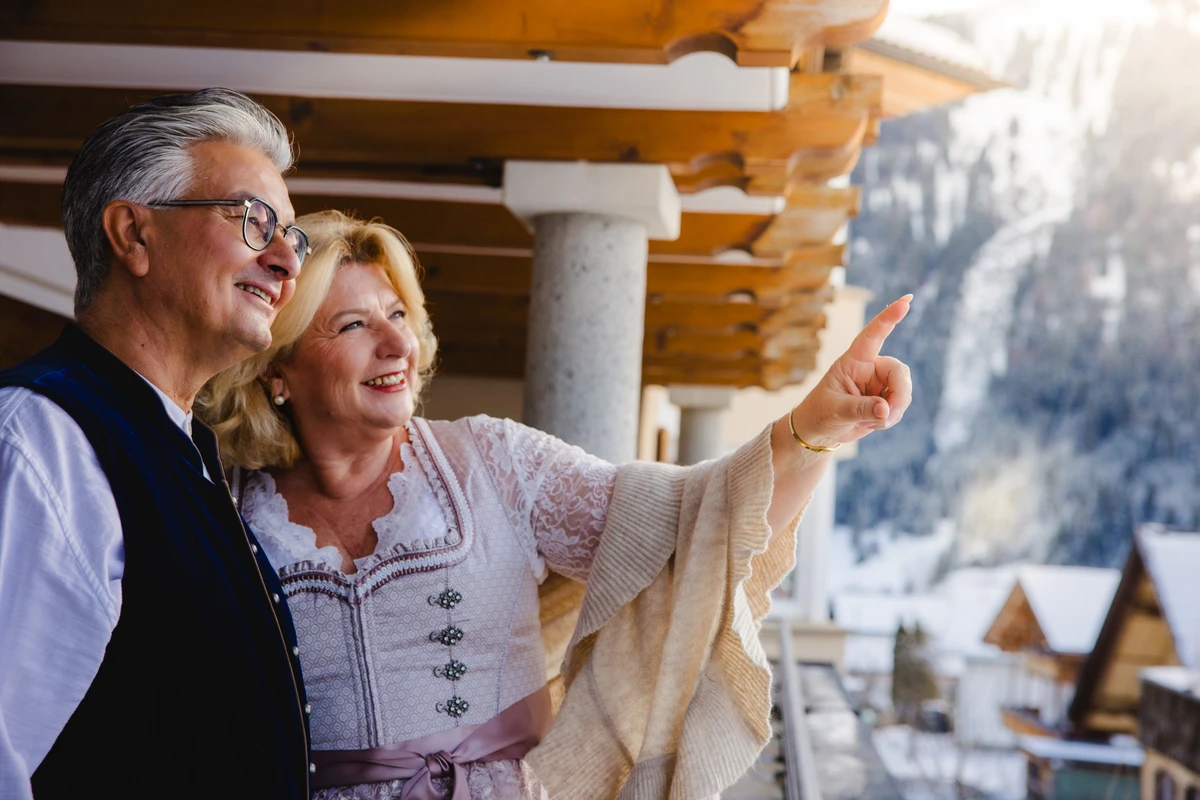 Frau im Dirndl und Mann betrachten verschneite Berge. Fotografin: Manuela Engelking. Aufnahmeort: Tirol.