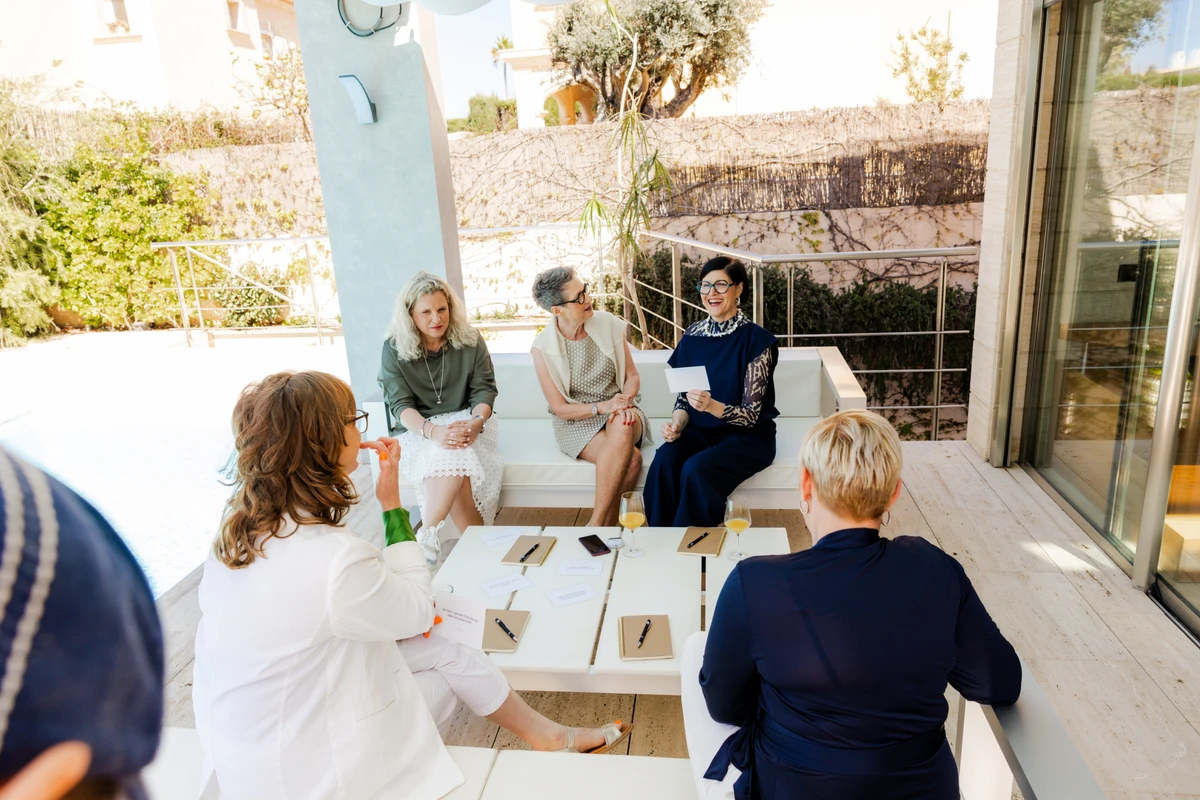 Frauen sitzen zum Austausch an einem Tisch auf einer sonnigen Terrasse